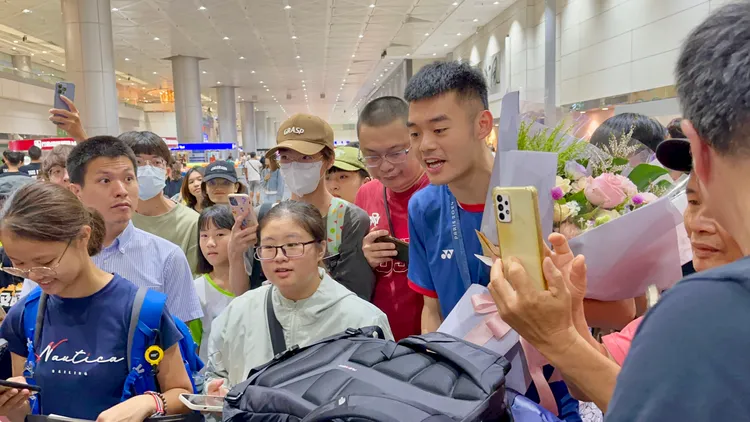 王齊麟推著行李車跟在羽球搭檔李洋後面，跟球迷合照。特勤中心攝