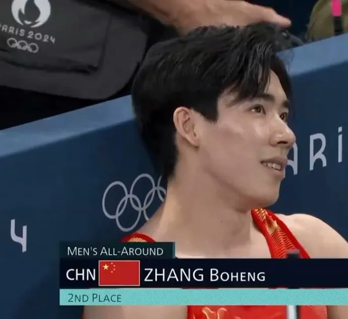 中國選手張博恒在體操男子個人全能決賽只拿下銀牌，看著計分板苦笑。翻攝微博