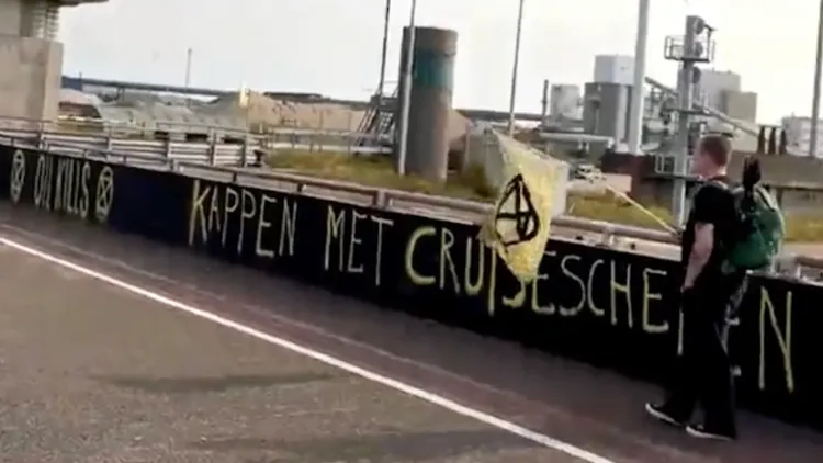 「反抗滅絕」環保人士在矮牆上噴漆，上面寫著「石油殺人，攔住郵輪」。翻攝自XR tv