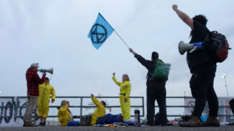 數名「反抗滅絕」環保人士在船閘上集會抗議並揮舞旗幟。翻攝自X@NLRebellion