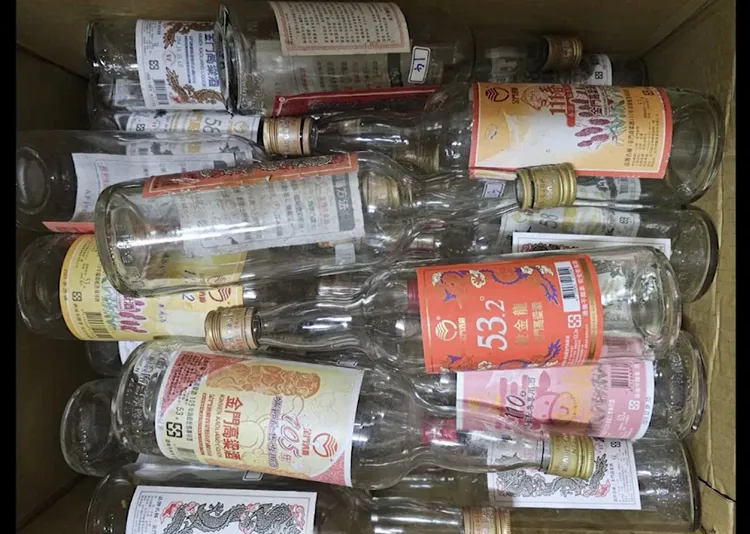 假酒集團成員收集金門高粱空瓶，清洗完後再裝入私釀高粱，貼上偽造標籤等，販售牟利。警方提供