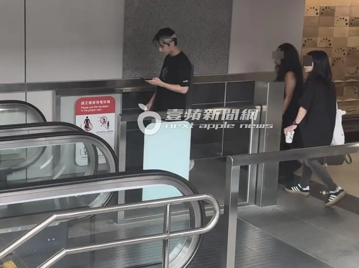 炎亞綸（左）邊傳訊息，搭乘手扶梯下高鐵南港站月台。特勤中心攝