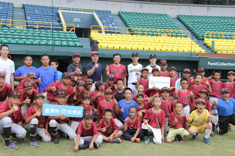 博田院長謝榮豪、金潭校長簡仲信與台鋼雄鷹隊投手小野寺賢人、捕手陳世嘉與金潭少棒隊合影留念。翻攝畫面
