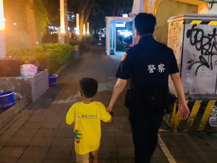 警員帶著男童在公園周邊找尋親人。平鎮警分局提供