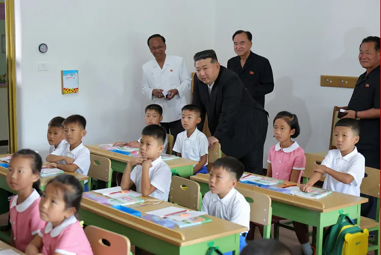 金正恩把手撐在學童的椅子後聽課。勞動新聞