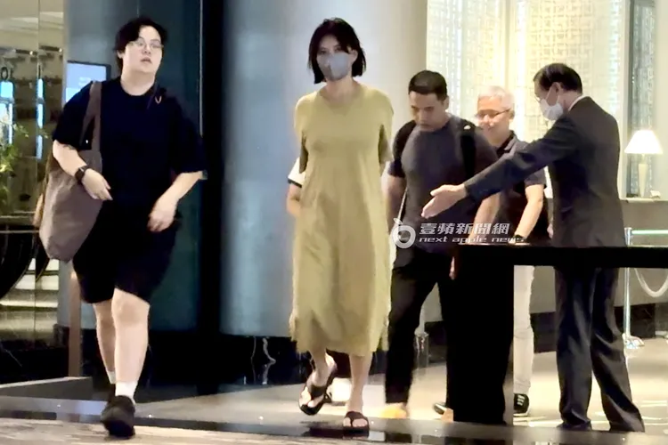 孫燕姿雙手放在身後，在飯店人員提醒下小心走過階梯。特勤中心攝