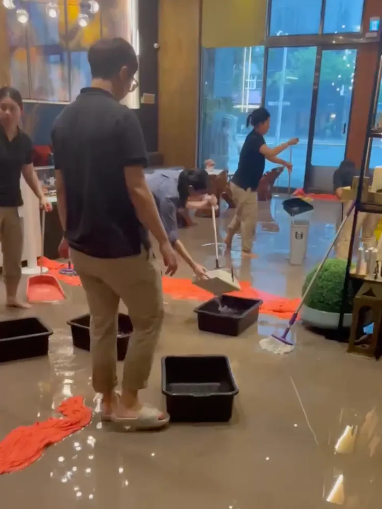 虎航特約飯店於颱風時大淹水，不少人正忙著用塑膠盆、掃把等將水排除。取自虎航工會臉書