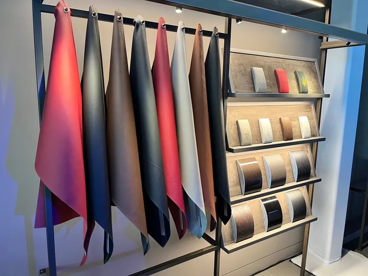 柔和燈光照耀下的牆面展示區，配有可滑動的暗色玻璃面板，展示著像珠寶般陳列的輪圈與方向盤，以及手工打造的柔軟皮革樣本。周奕豪攝