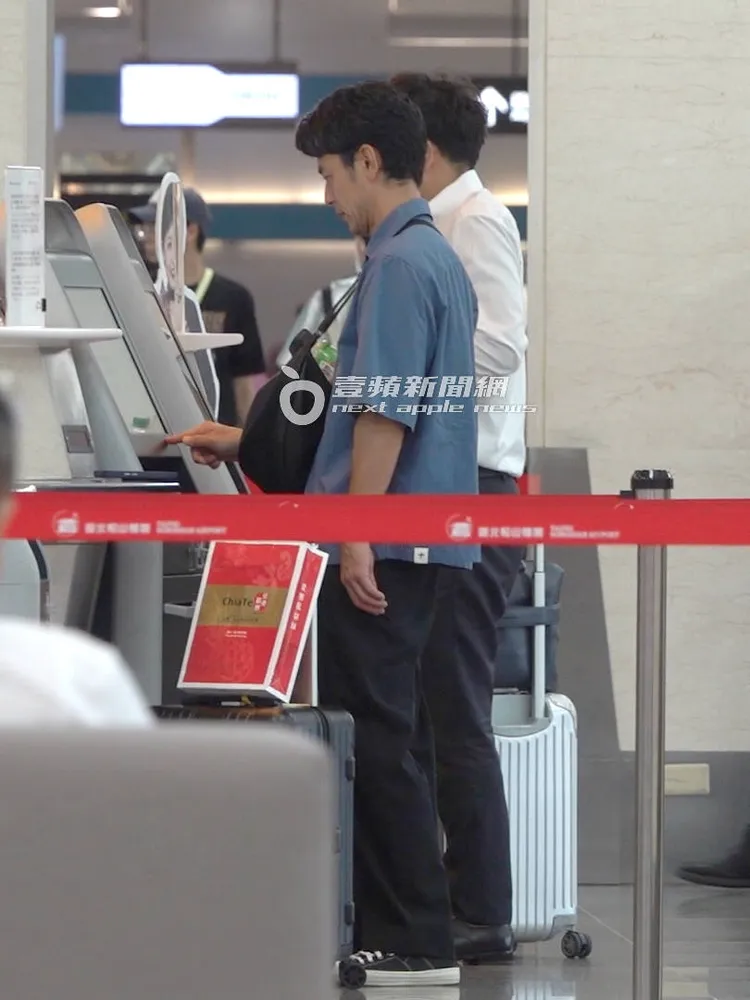 妻夫木聰獨自在機場自助報到機器前操作。特勤中心攝