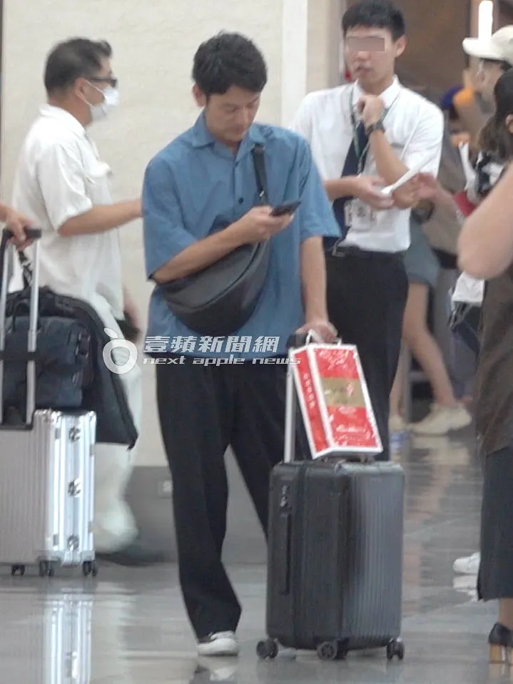 等待時，妻夫木聰自己推著行李箱掛著鳳梨酥邊滑手機。特勤中心攝