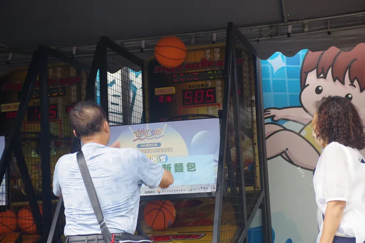公館商圈舉辦「2024愛戀公館-街頭不插電音樂會X投籃爭霸賽」，現場投籃機爭霸賽讓民眾小試身手。商圈提供