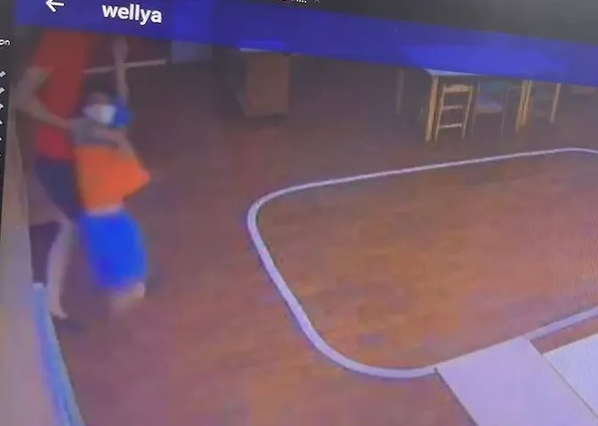 女老師左手抓著男童左手腕，右手抓著他右上臂，將他提進教室內。江和樹提供