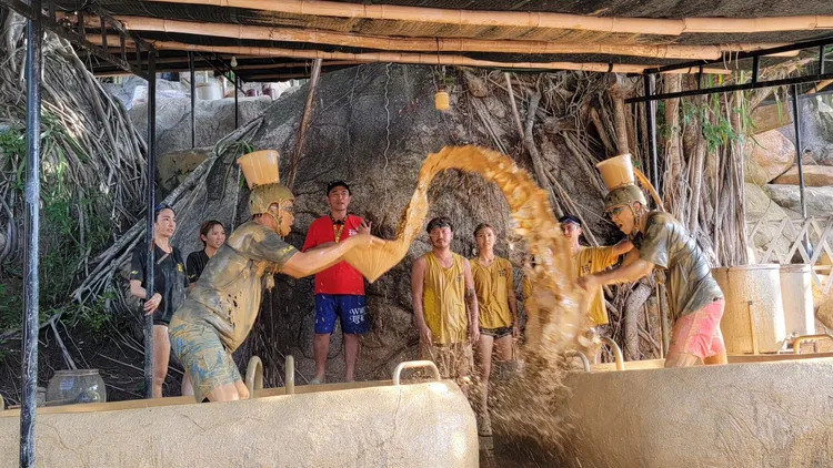 黃鐙輝（左起）、坤達出外景，玩遊戲時要收集頭頂桶子的泥漿數量，結果2人滿身是泥巴。好看娛樂提供