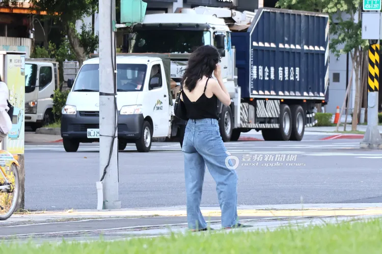 田燕呢在十字路口站三七步看手機等綠燈。特勤中心攝