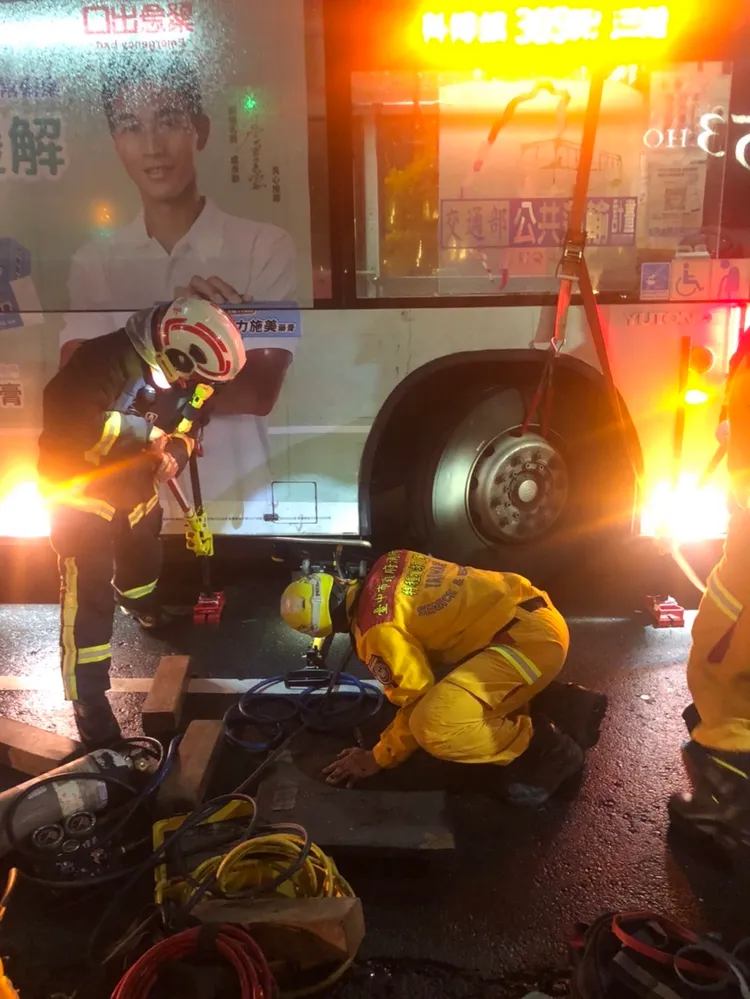 消防人員以器材抬起公車車輪，救出受困的林姓女大生，但仍因傷重不治。民眾提供