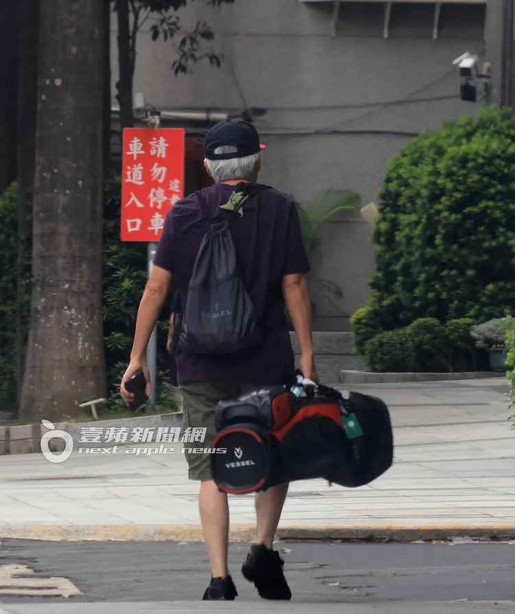 張宇一手拿手機一手提著整組球具，步伐穩健。特勤中心攝
