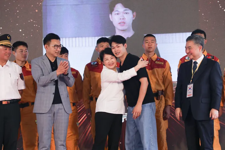 921地震倖存者張景閎也回到現場獻花，他說，當年僅6歲的他被埋在房屋地下室86小時，事發後一片黑暗，被韓國119救助隊救出，今到場感謝韓方救援。會中，盧秀燕市長也向張景閎獻上擁抱。台中市府提供