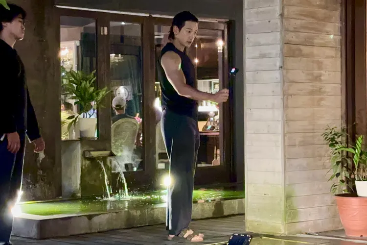 Rain（右）換穿吊嘎背心，秀出結實大肌肉，腳踩勃肯鞋運鏡，記錄下川菜餐廳的庭院流水造景。特勤中心攝