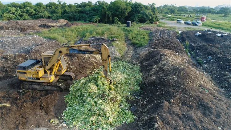阿仁開怪手在農場裡將菜葉與泥土混合，以便發酵。無米樂影像工作室提供