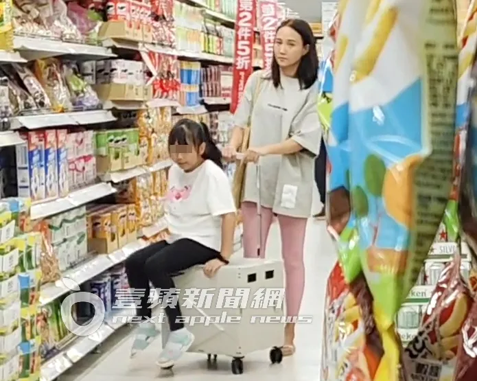 小女兒呱呱（左）買完餅乾坐上推車讓何妤玟推。特勤中心攝