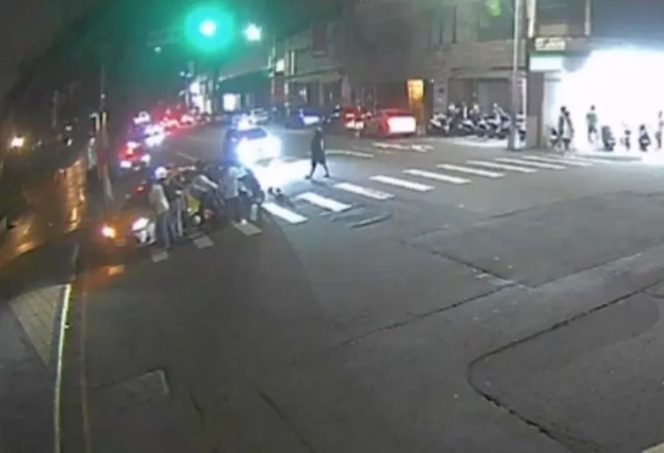 騎士卡在計程車車底，熱心路人合力將車子抬高，救出受困的騎士。民眾提供