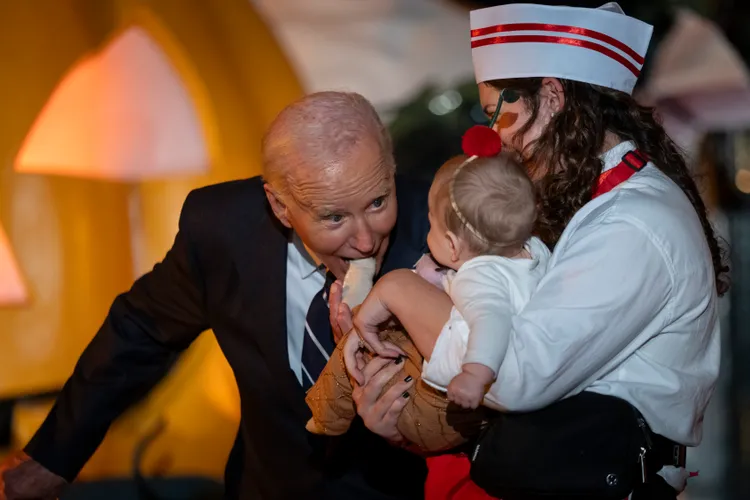 拜登作勢要咬嬰兒的腳趾。美聯社