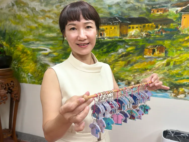 高市客委會主委楊瑞霞指合唱團孩子們手作藍衫吊飾，希望日本受災民眾「安全久久、健康久久、台日友誼也能長長久久」。市府提供