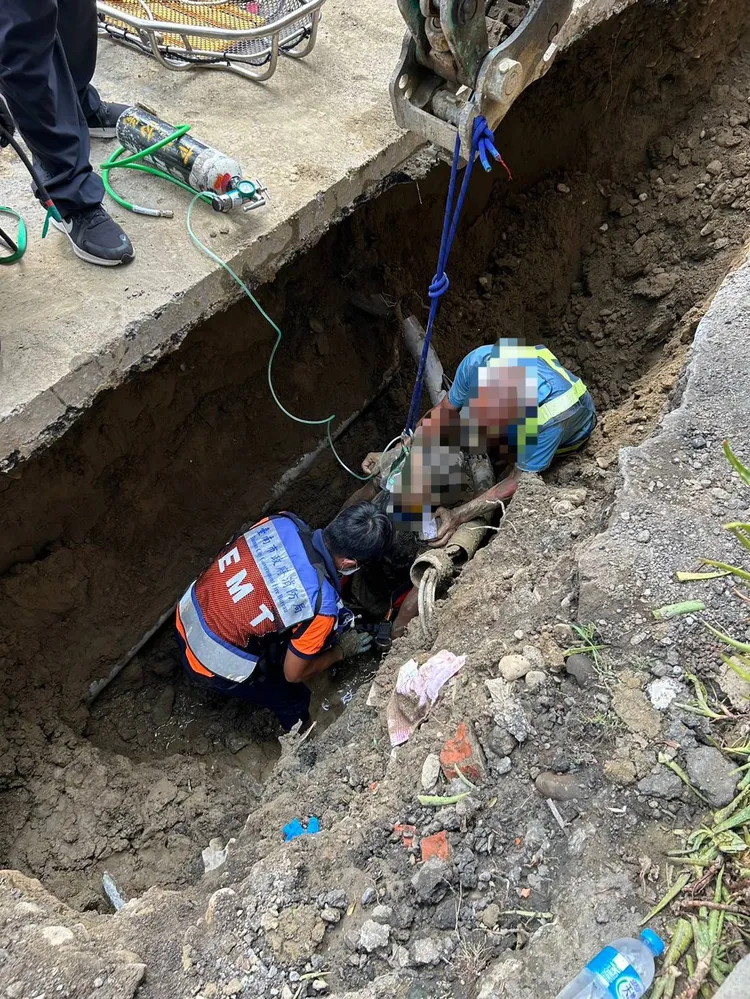 警消到場挖掘軟土，再用繩索固定，吊車將人拉起脫困。讀者提供