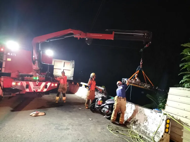 消防人員以器材車吊掛，將廖男救起，他的機車就在一旁。讀者提供
