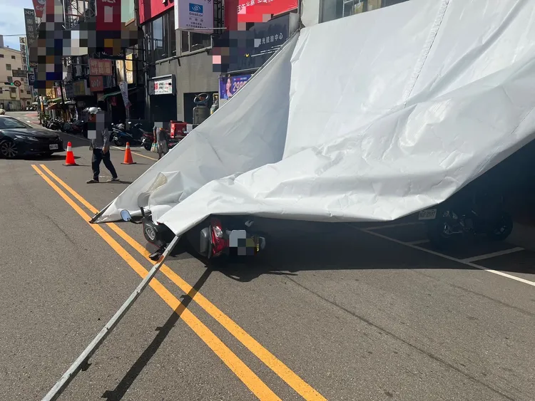 大型帆布招牌被強風吹落，擊中路過女騎士。民眾提供