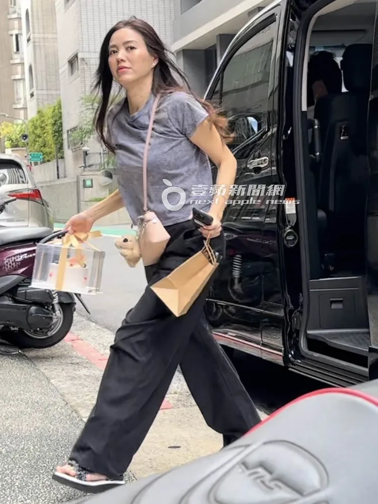 林牧潔長髮飄逸，手提高級透明蛋糕禮盒下車。特勤中心攝