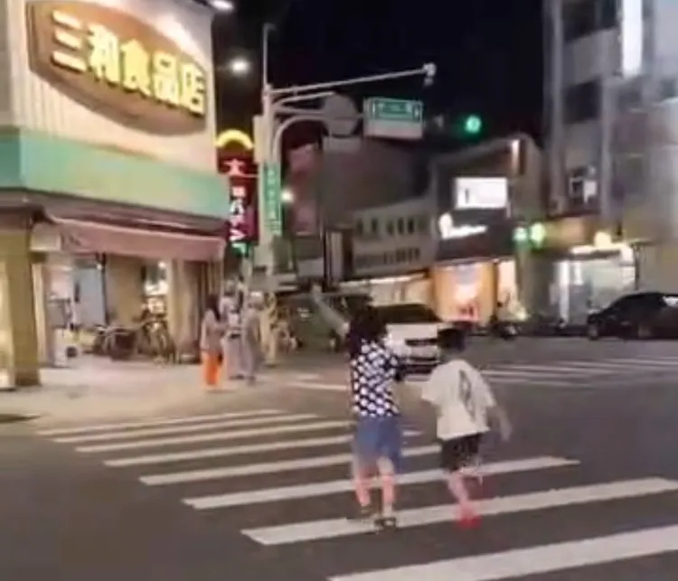 嘉義市一對姊弟過馬路，高舉雙手示意駕駛注意，相當可愛。取自臉書