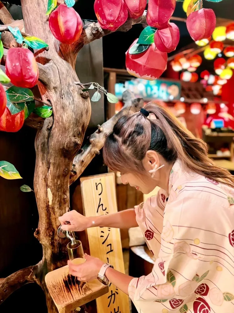 段慧琳在青森「歡騰蘋果祭」，扭開樹幹上的水龍頭，竟流出蘋果汁。民視提供