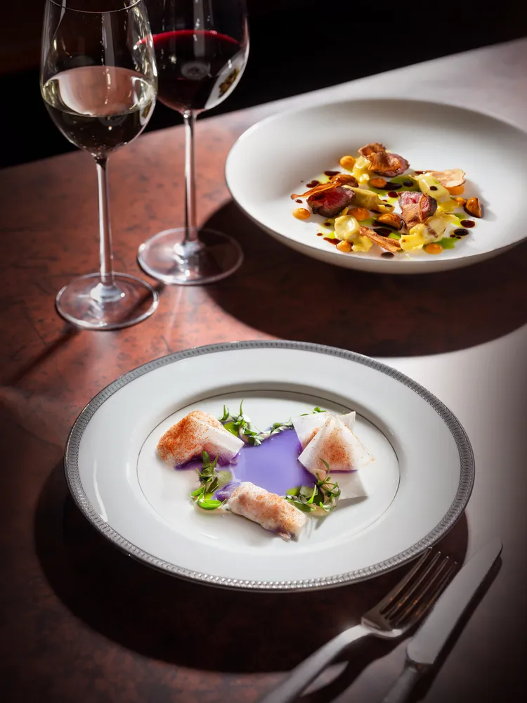 《醃漬黃尾獅魚塔塔、綠胡椒油、大根、紅甜椒》將黃尾獅魚切成小塊並以些許鹽跟糖輕醃調味，由輕薄透光的大根薄片巧緻包裹，佐以蝶豆花淡雅渲染的清爽番茄湯汁，綴以綠胡椒油輕柔妝點。業者提供