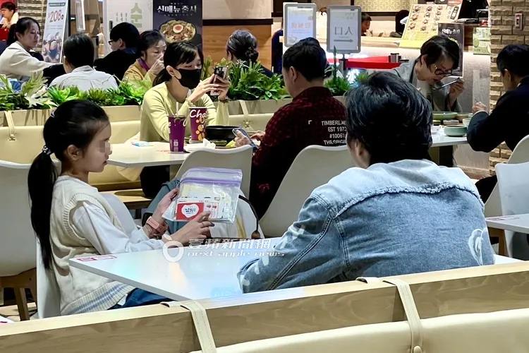 藍正龍（右）與9歲女兒在美食街等周幼婷和兒子點餐回來。讀者提供