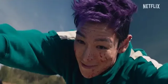 T.O.P預告中故意推前方的參賽者連環倒，露出狡猾的表情喊「再見」。翻攝Netflix