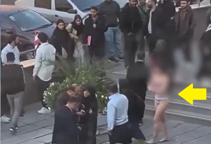 伊朗女大生獨自一人（黃箭頭）抗議服裝規定，校園中其他人冷眼旁觀。翻攝Ｘ＠Amir Kabir