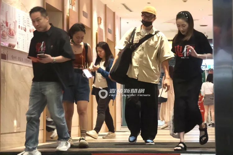 錢人豪（左）拿著手機叫計程車，與尹馨（右）隔著工作人員保持安全距離。特勤中心攝