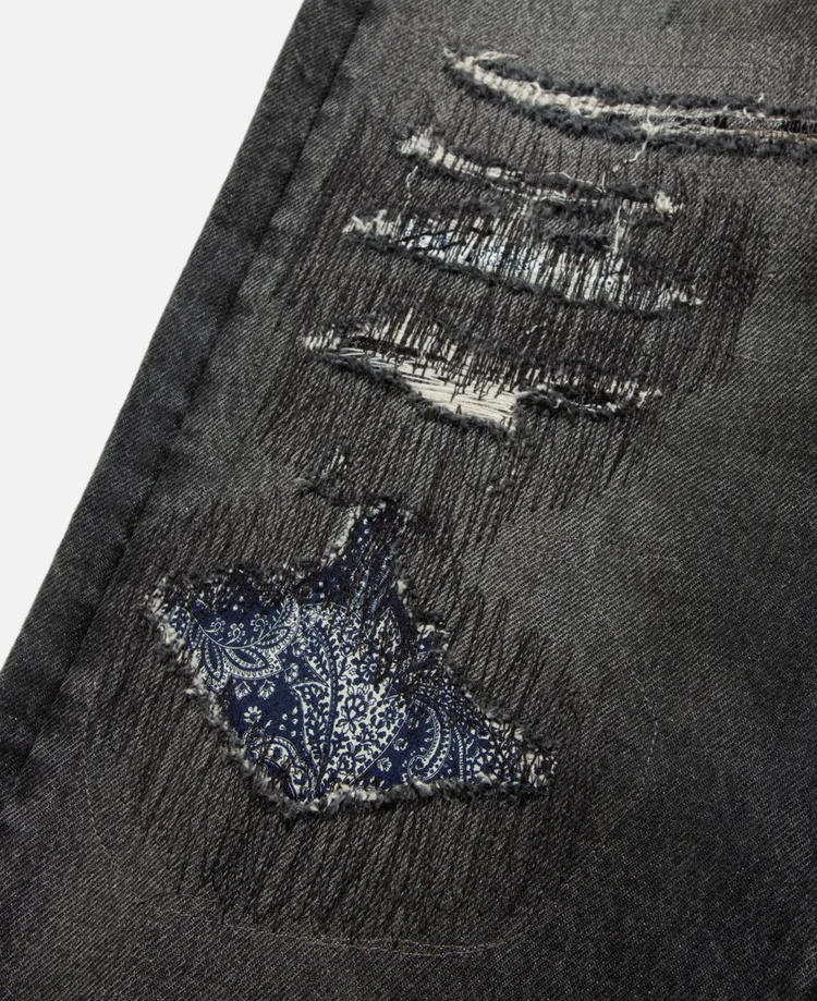 褲身前方大膽使用格紋以及腰果花紋布料的破壞細節，增添了原創性視覺層次。品牌提供