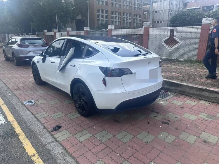 特斯拉被砸到車窗玻璃全碎，車燈、車身也受損。民眾提供