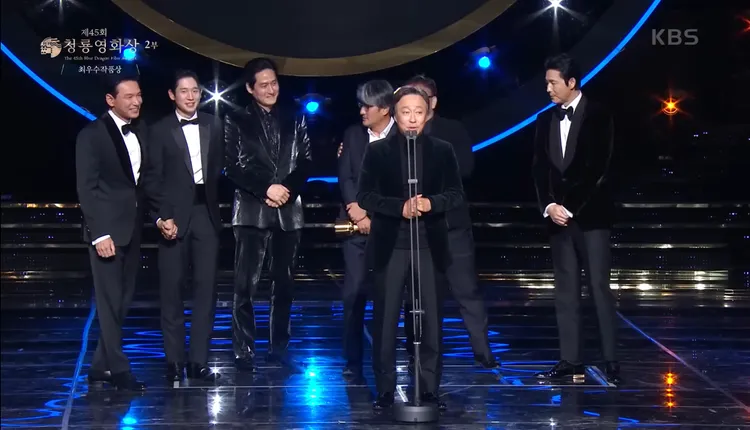 《12.12：首爾之春》獲頒最佳影片，黃晸玟（左起）cue丁海寅上台，所有人沉浸在歡樂的氣氛，跟鄭雨盛（右）形成強烈對比。翻攝KBS