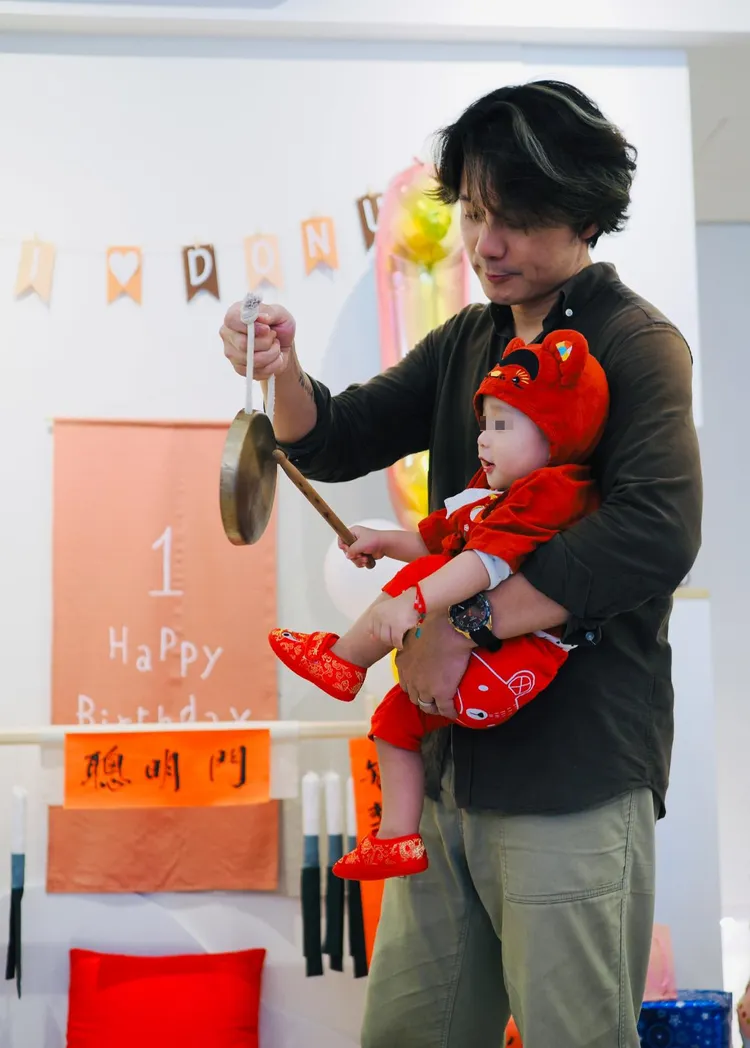 廖科溢抱著兒子讓他自己敲吉祥鑼。翻攝秦綾謙臉書