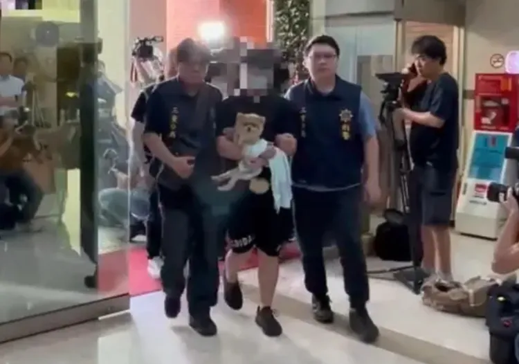 張男被逮捕時進入警局，懷中緊抱著岳母養的博美狗「糯米」。翻攝畫面