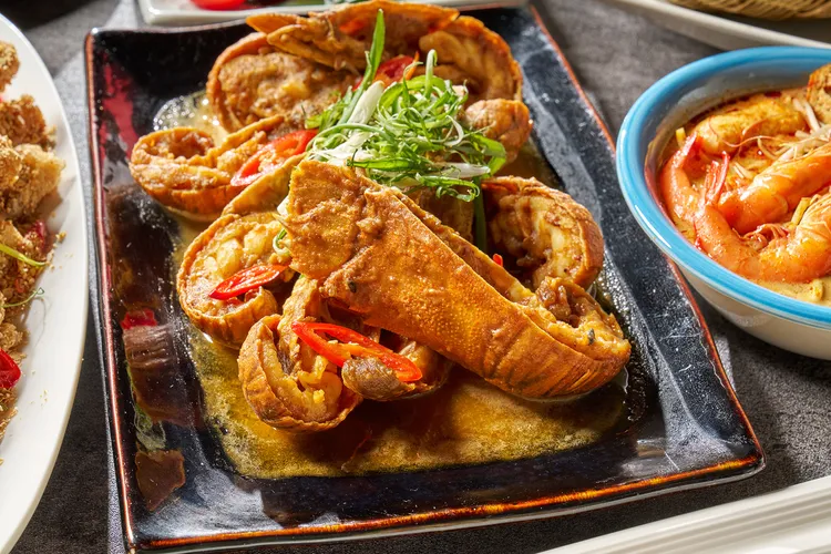 新加坡鹹蛋黃炒蝦蛄，將炸好的蝦蛄拌入以鹹鴨蛋黃、蒜頭、泰國辣椒和香氣濃郁的咖哩葉調製而成的濃郁奶油醬汁中。業者提供