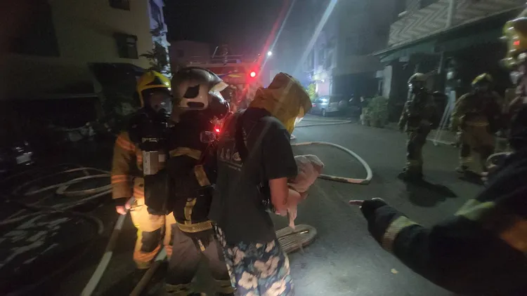 消防人員登梯入內，將躲在房間的一家三口救出。民眾提供