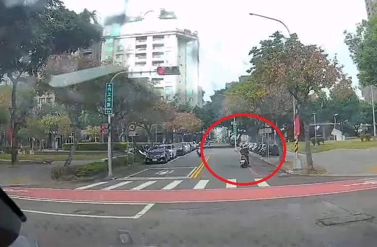 女騎士差點被公車撞飛，通過路口後停在路邊恢復情緒。讀者提供