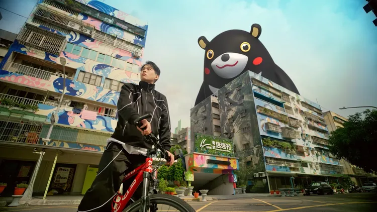 張庭瑚騎進迷迷村，為四周充滿藝術感的建築著迷。市府提供