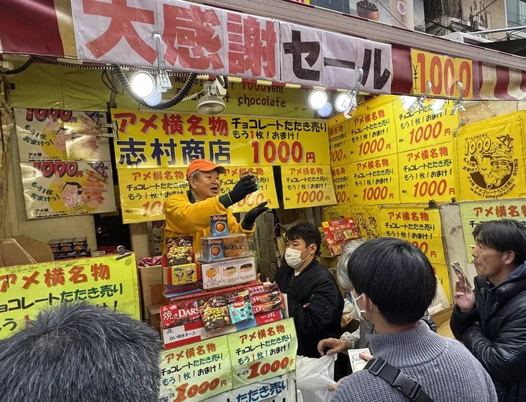 東京上野阿美橫近日湧入大批前來購買年菜食品的民眾，販售巧克力的店家「志村商店」老闆叫賣術高超，經媒體報導後，生意興隆。 中央社