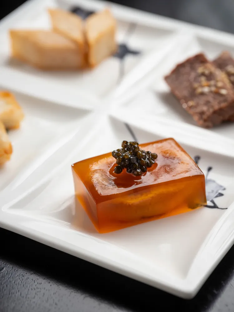 主廚經典菜式「魚子醬水晶鮑魚」將九頭鮑魚以雞肉與豬肉熬製的高湯
燜煮三小時後，入味且口感彈牙，再以金華火腿、老母雞與豬肉製成的上湯明膠包覆成凍，上頭並加上魚子醬點綴提味。業者提供