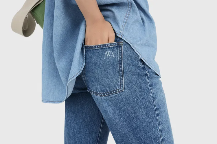 女裝直筒牛仔褲在背面口袋以同色系JWA標誌裝飾點綴。品牌提供